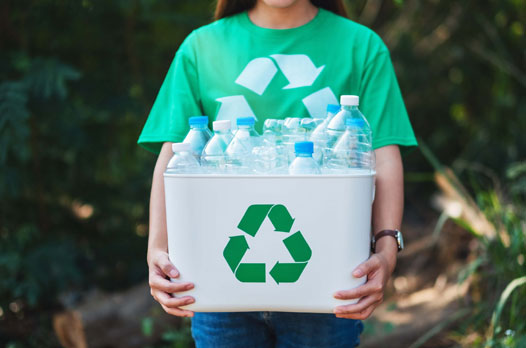 A women collecting and holding recyclable plastic bottles in a trash bin